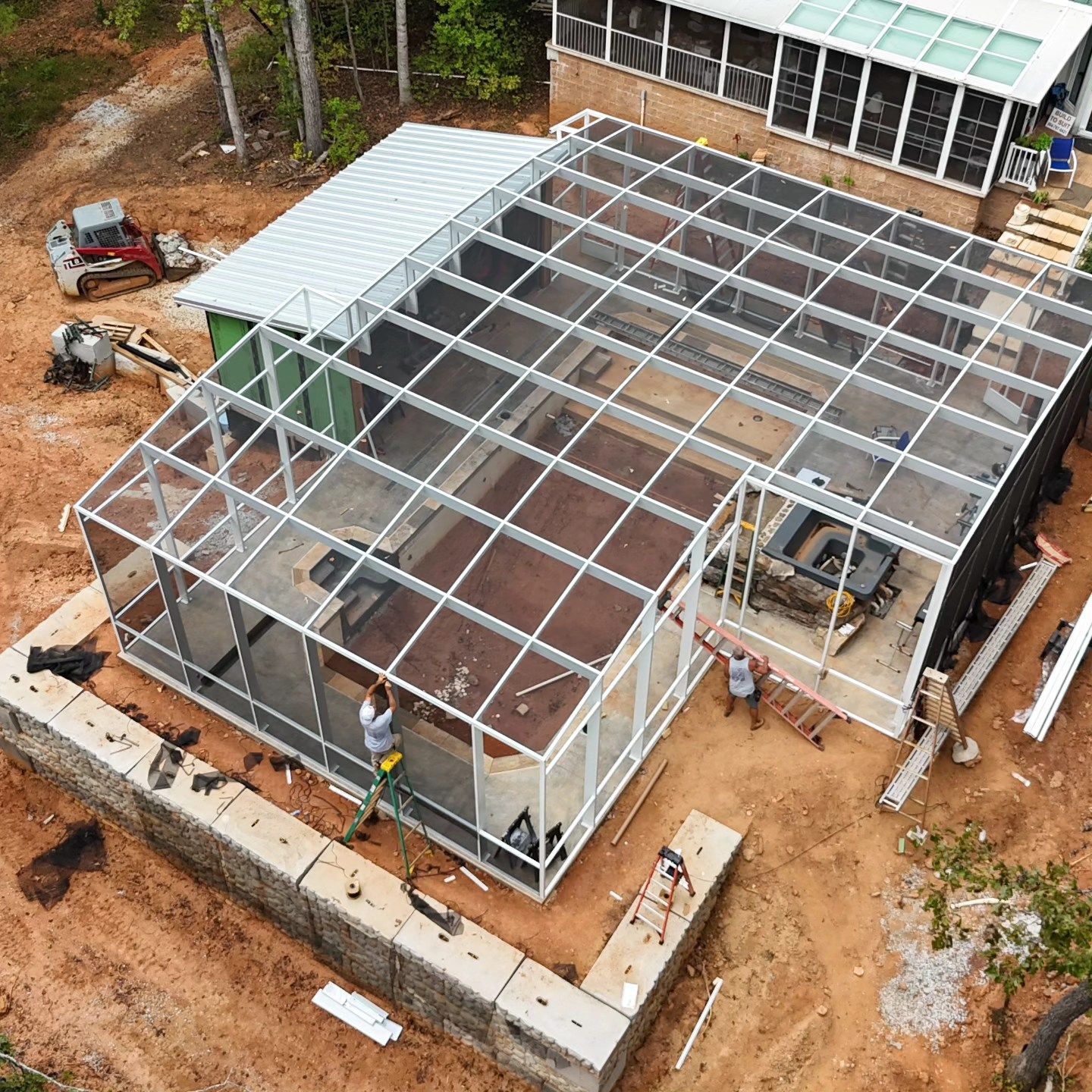 An aerial view of a greenhouse being built in the middle of a dirt field.