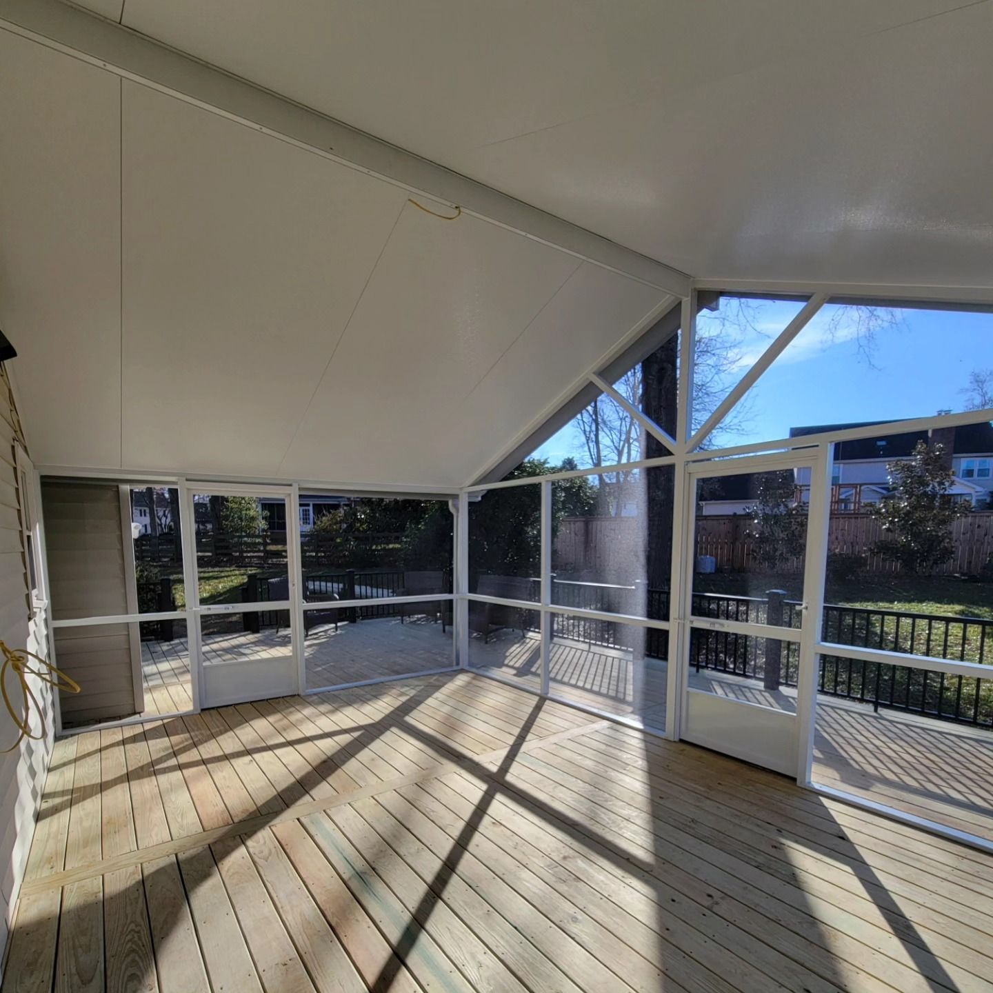 A screened in porch with a wooden deck and lots of windows