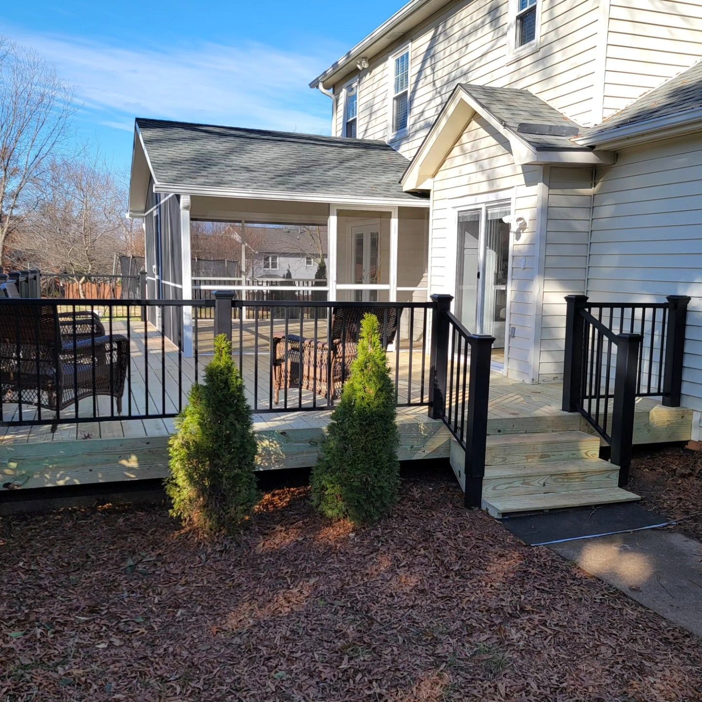 A white house with a screened in porch and a wooden deck.