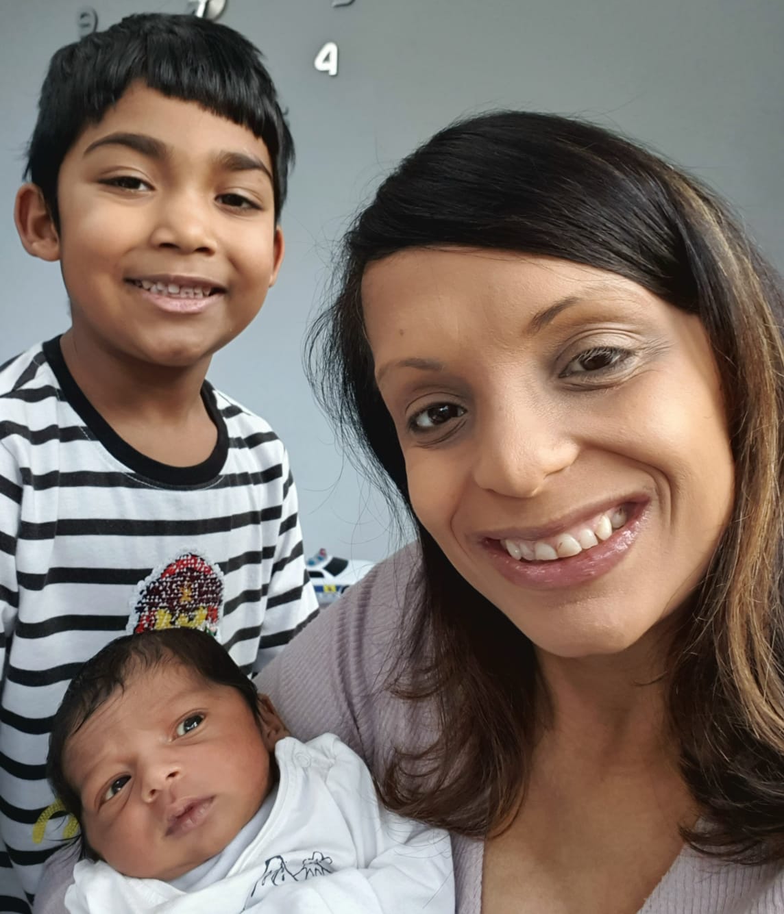 Mother smiling with newborn and older sibling after a joyful birth experience