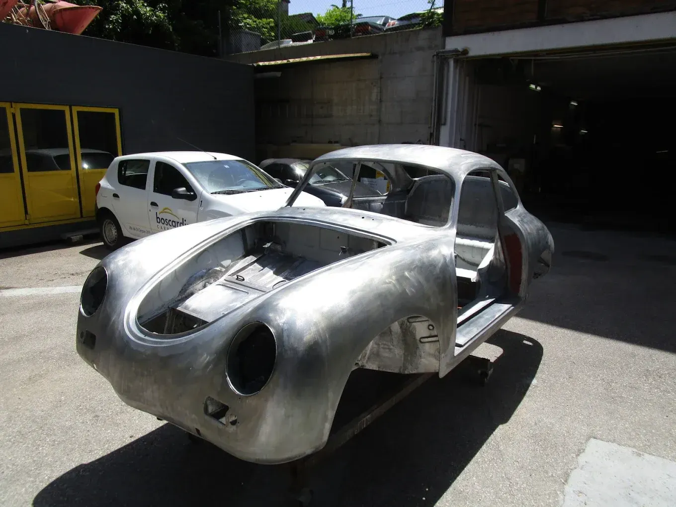 Une voiture argentée est garée sur un parking à côté d'une voiture blanche.