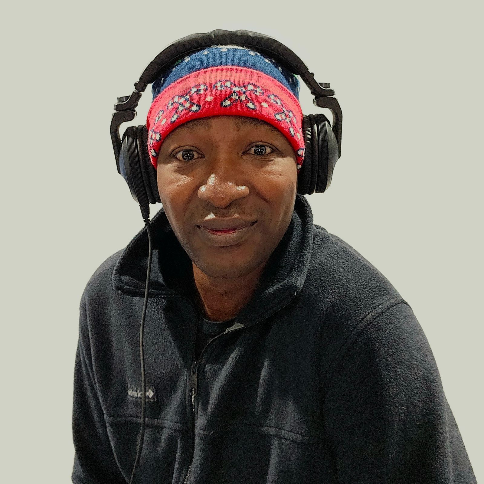DJ Aaron Harris wearing headphones, a winter hat, and a black jacket, looking at the camera.