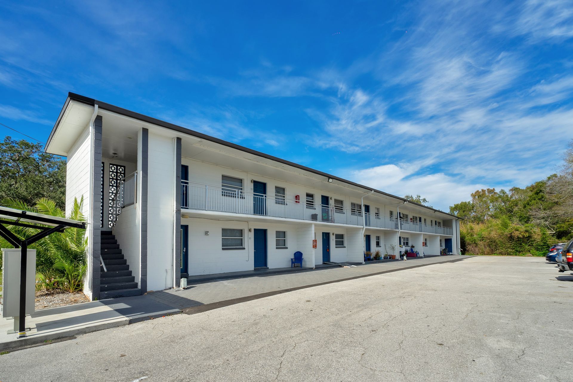 A large white building with stairs and a parking lot in front of it.