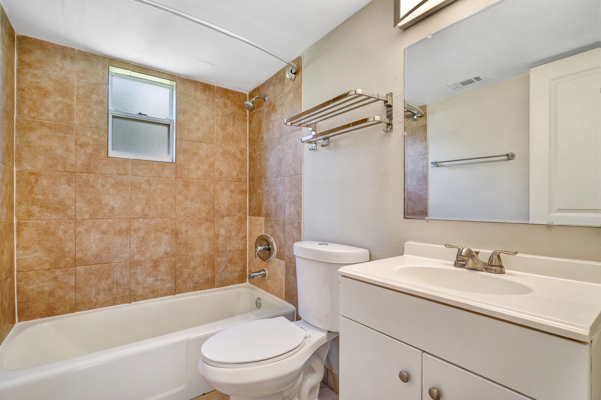 A bathroom with a toilet , sink , tub and mirror.