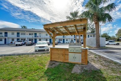 A wooden grill is sitting in the grass in front of a building.