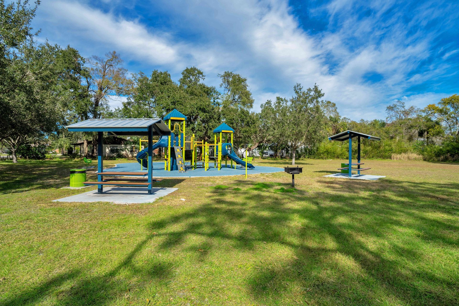 A playground in a park with a picnic table and a shelter.