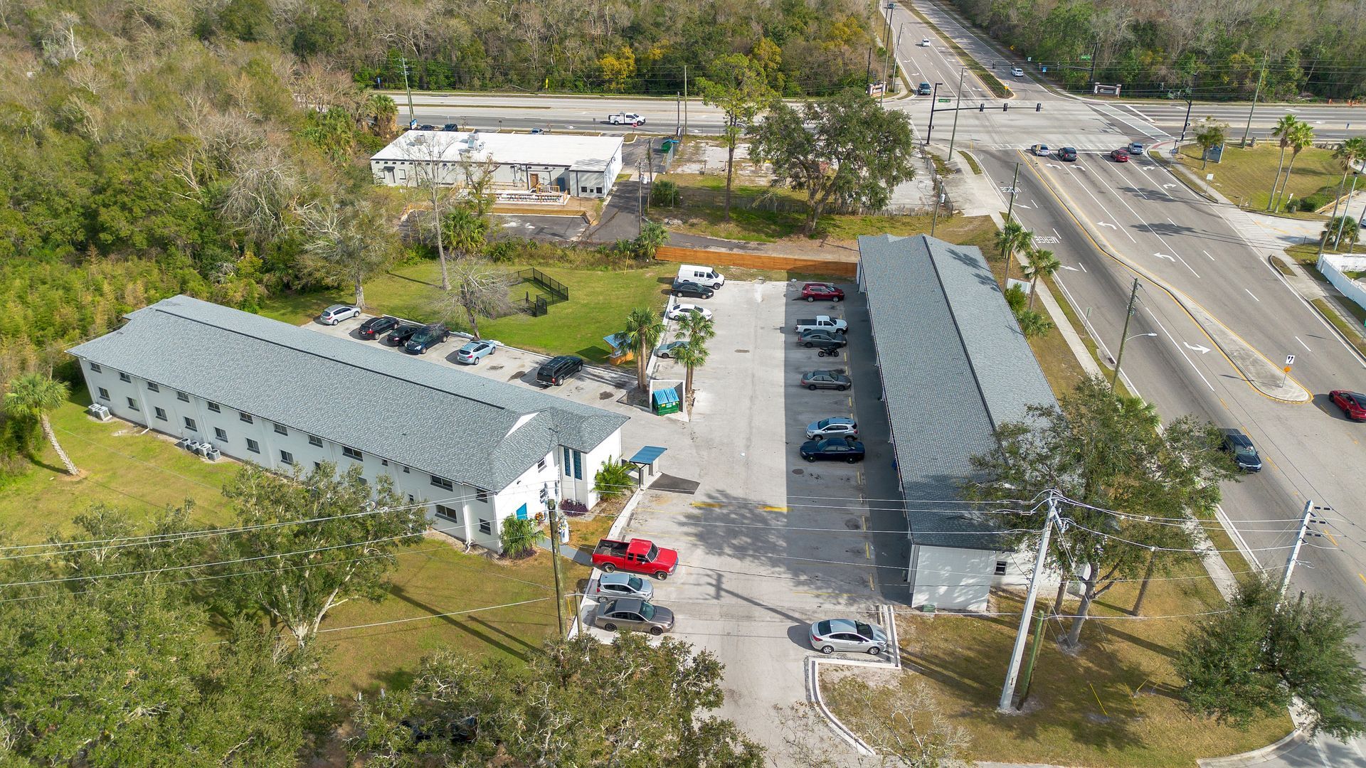 An aerial view of apartment buildings with cars parked in front of it.