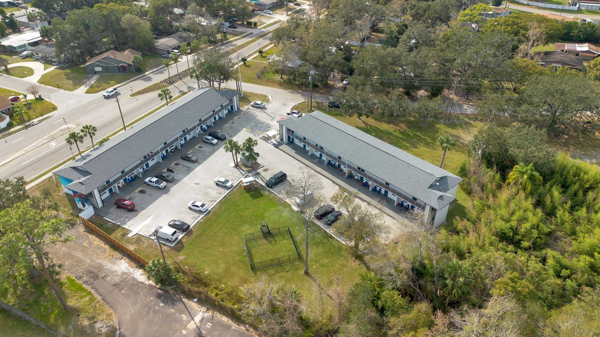 An aerial view of apartment buildings with cars parked in front of it.