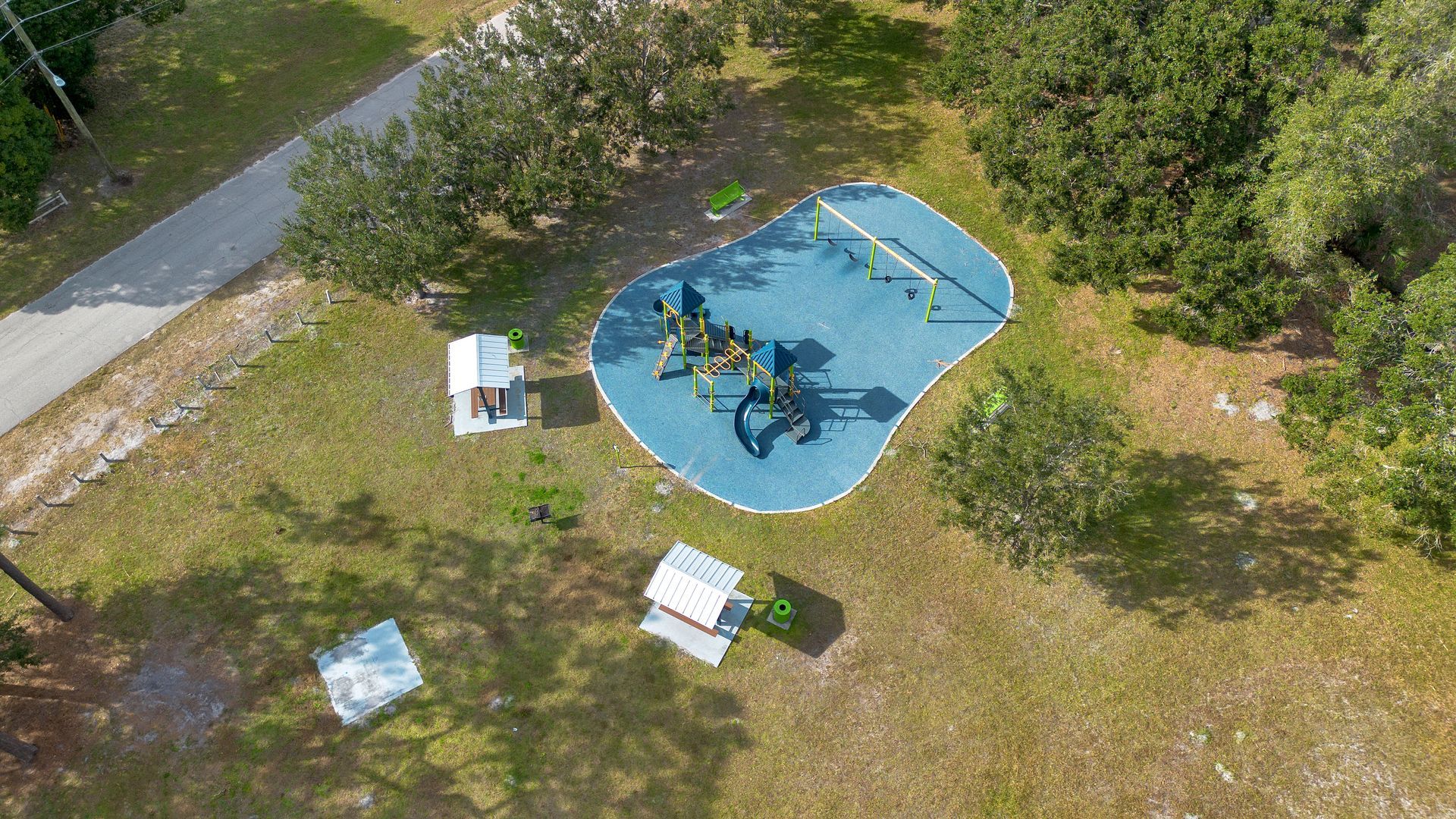 An aerial view of a playground in a park surrounded by trees.