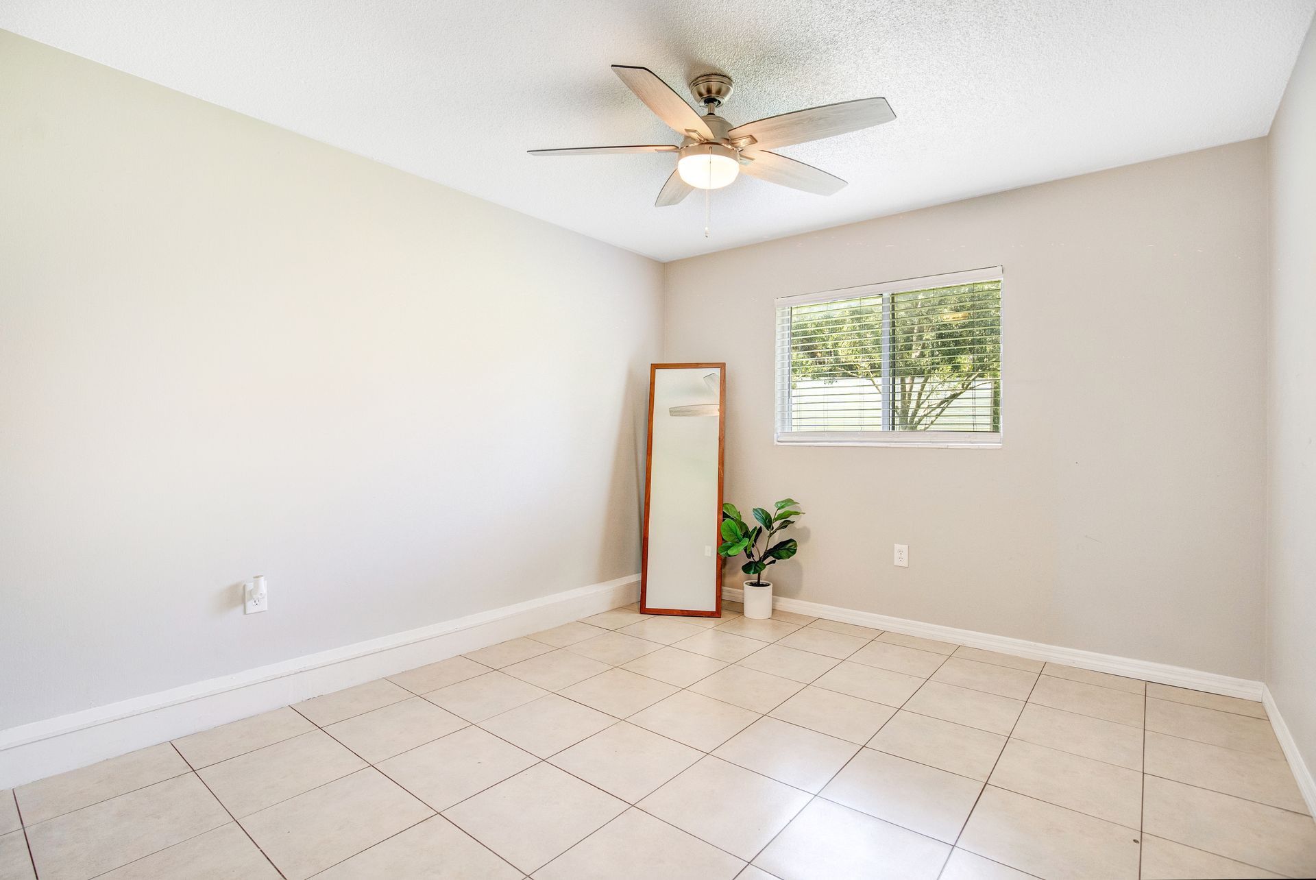 An empty bedroom with a ceiling fan and a mirror.