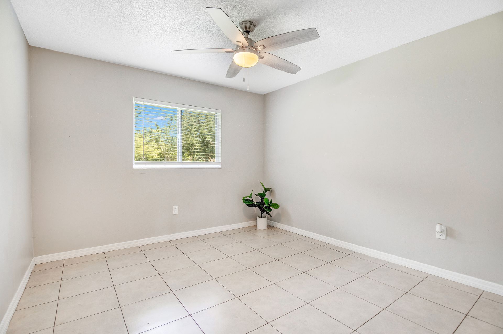 An empty room with a ceiling fan and a window.