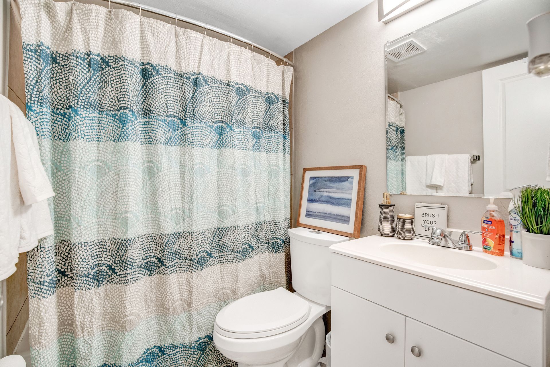 A bathroom with a toilet , sink and shower curtain.