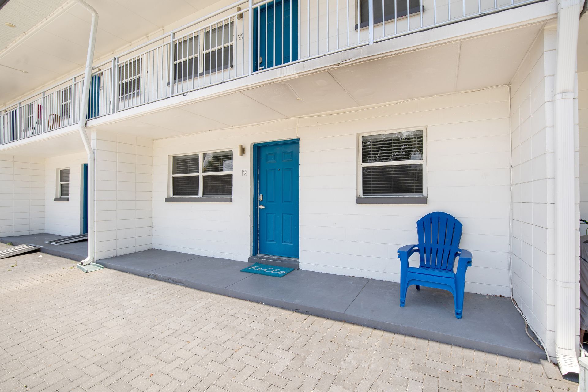 A blue chair is sitting on the porch of a white building.