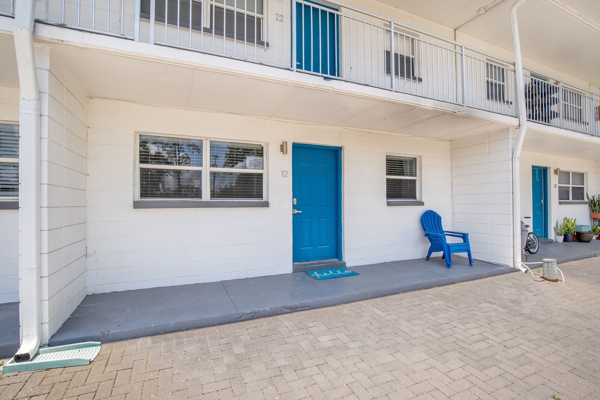 A white building with blue doors and a blue chair on the porch.