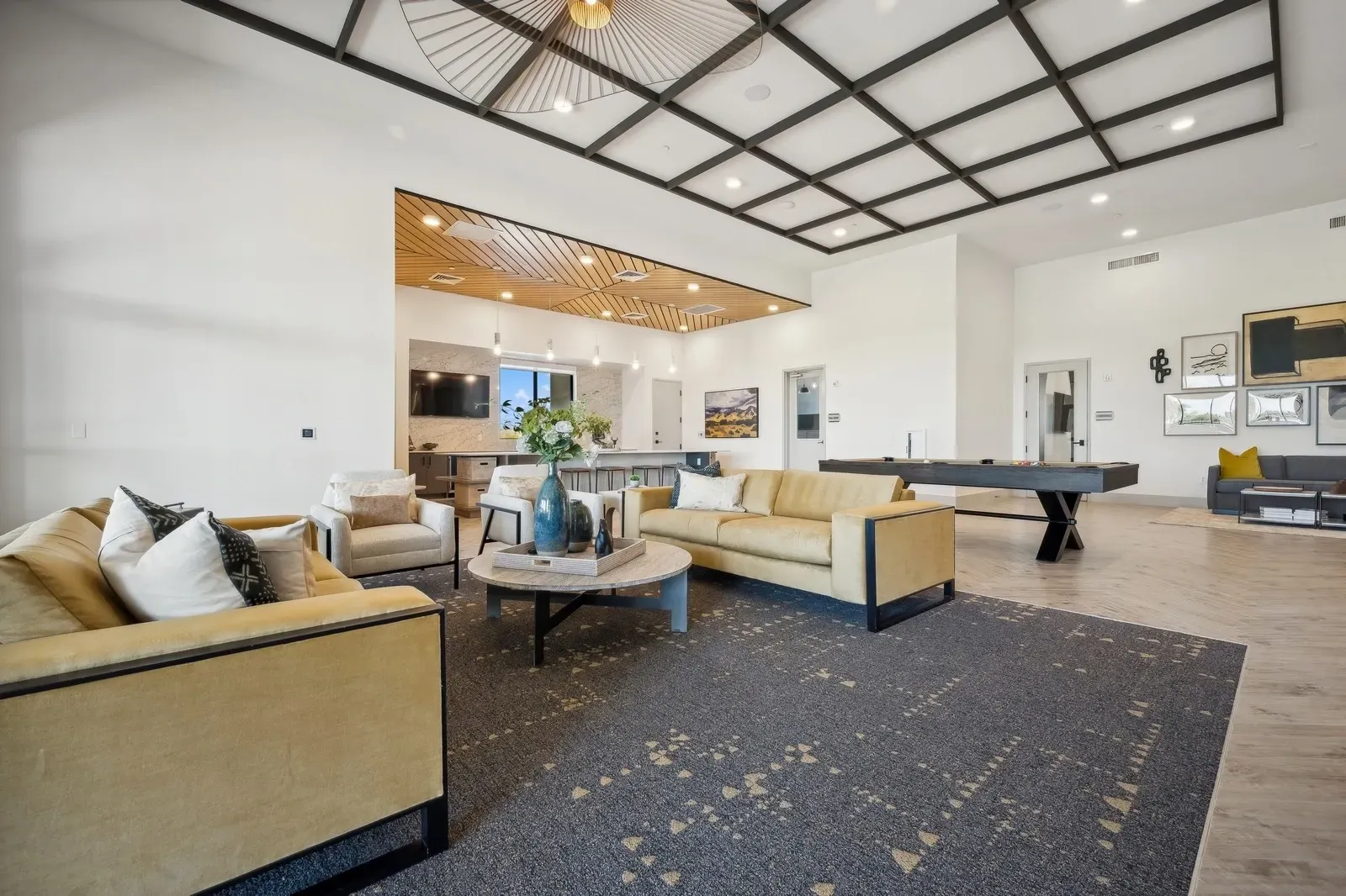 Modern lounge with beige sofas, black-and-white ceiling, patterned carpet, and a pool table