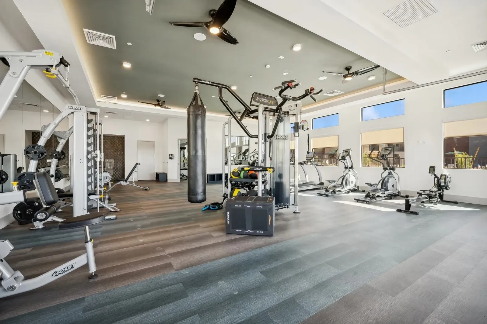 State-of-the-art fitness center featuring a wide array of cardio and strength training equipment, including treadmills, ellipticals, a rowing machine, weight machines, and a boxing bag for your workout needs.