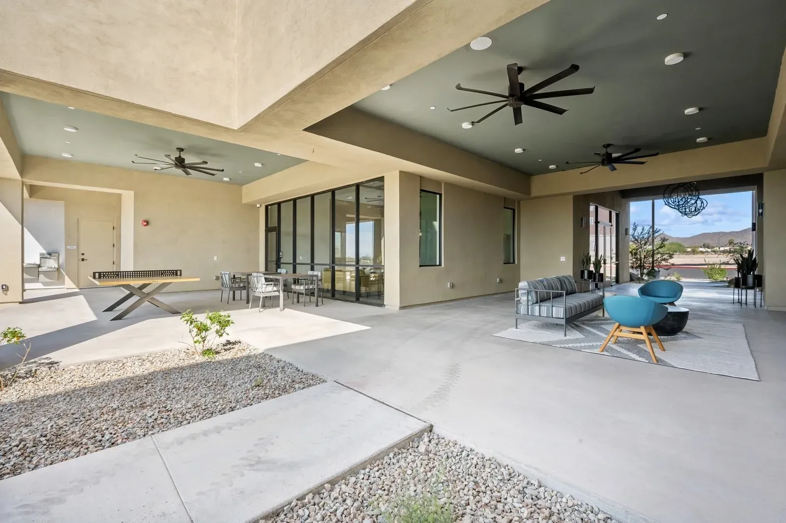 Relax and play in this stylish outdoor lounge area, featuring comfortable seating, a ping pong table, and dining tables, perfect for socializing.