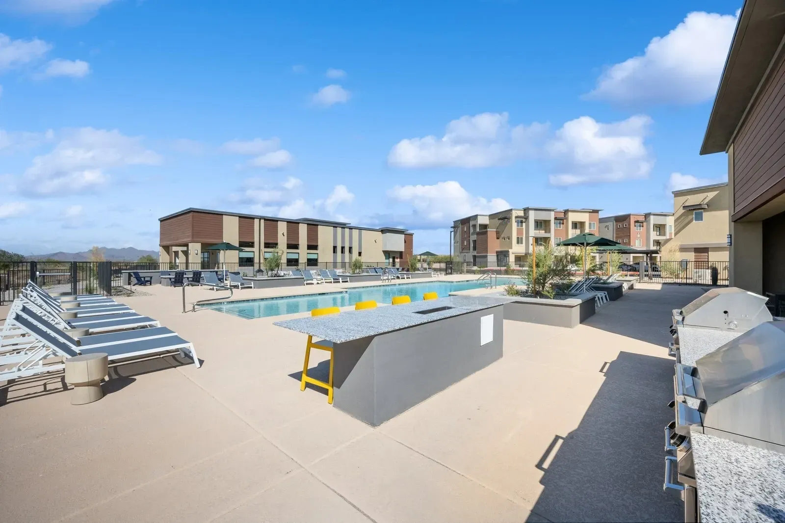 Enjoy the outdoors at our resort-style swimming pool, complete with comfortable lounge chairs, a modern outdoor bar, and BBQ grills for entertaining.