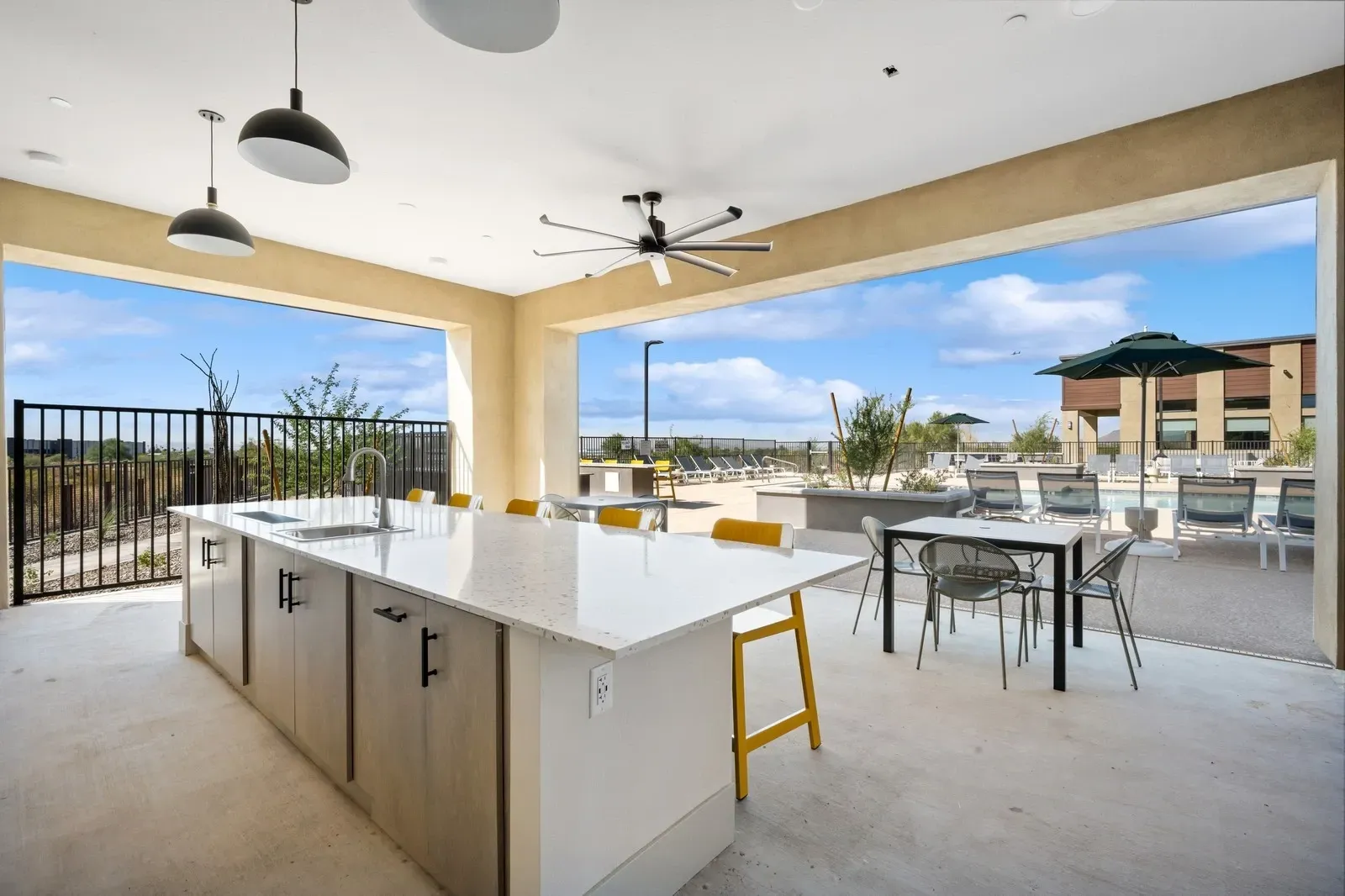 Enjoy cooking and dining al fresco with this modern outdoor kitchen, complete with a spacious island and seating, adjacent to a sparkling swimming pool and sun-drenched lounge area.