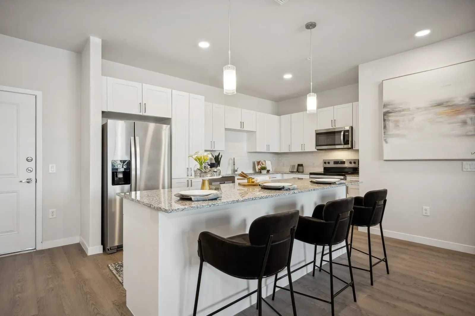 Sleek modern kitchen featuring a granite-topped island with bar stools, stainless steel appliances, and ample cabinet space.