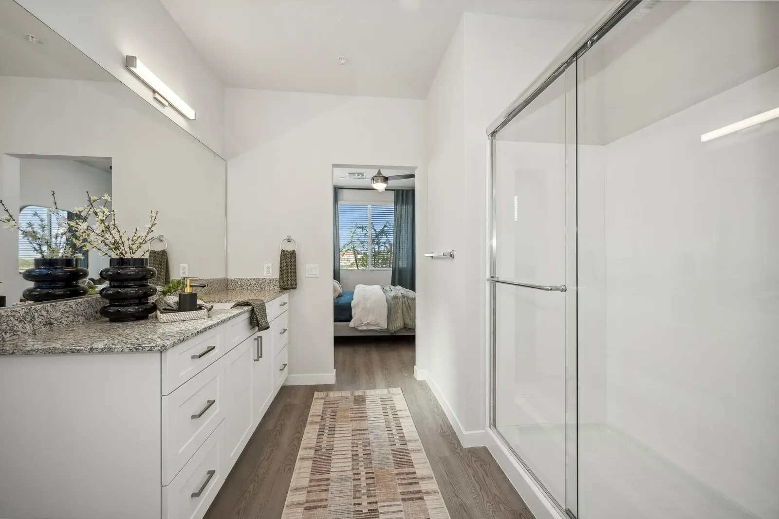 Bright white modern bathroom with double vanity, large mirrors, and a walk-in shower.