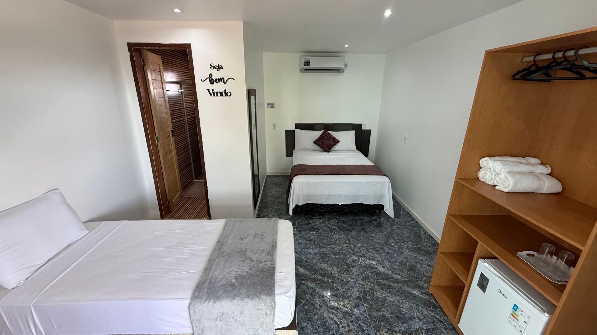 Um quarto de hotel com duas camas e uma geladeira.