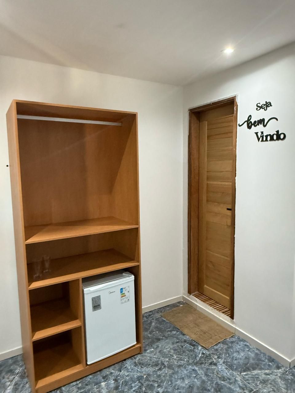 Uma sala com uma prateleira de madeira e uma pequena geladeira