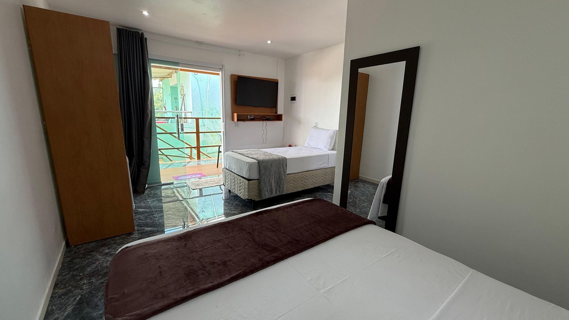 Um quarto de hotel com uma cama, espelho e televisão.