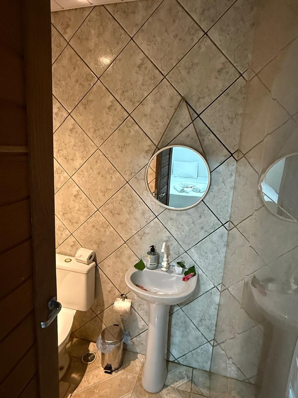 Um banheiro com pia, vaso sanitário e espelho.