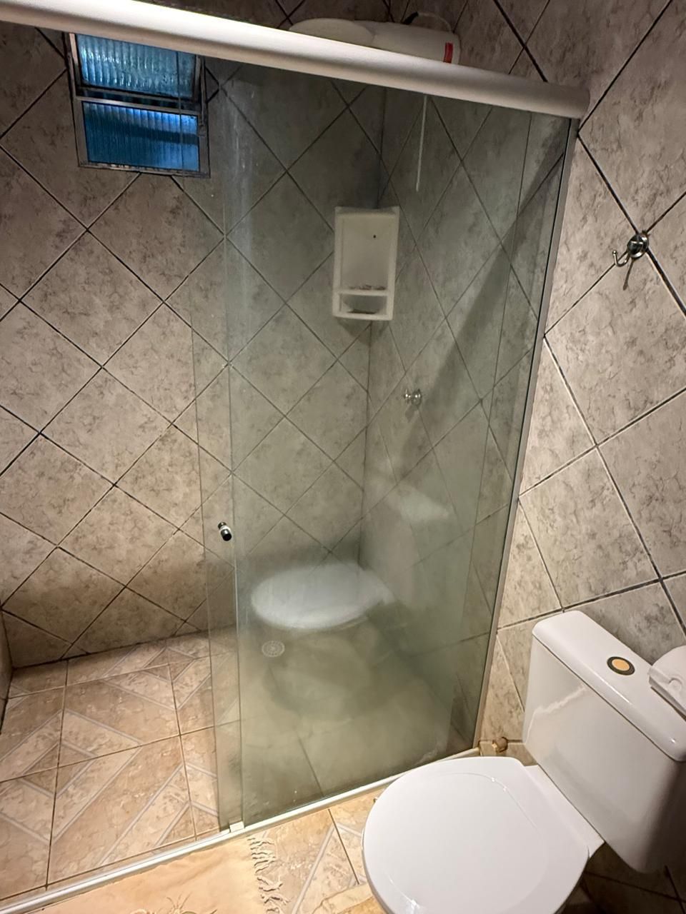 Um banheiro com vaso sanitário, chuveiro e porta de vidro.