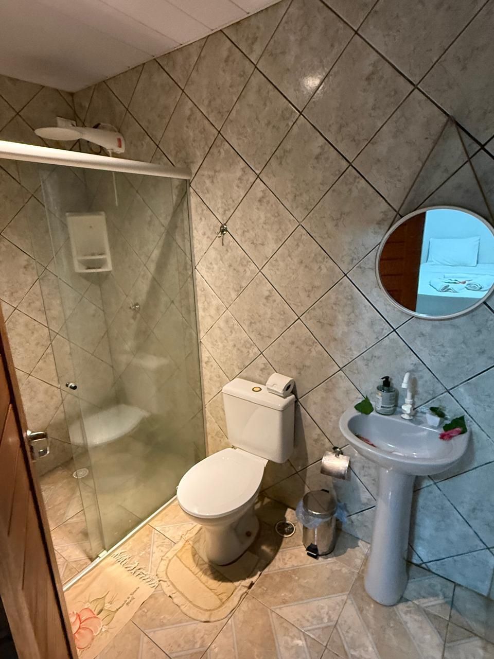 Um banheiro com vaso sanitário, pia, chuveiro e espelho.