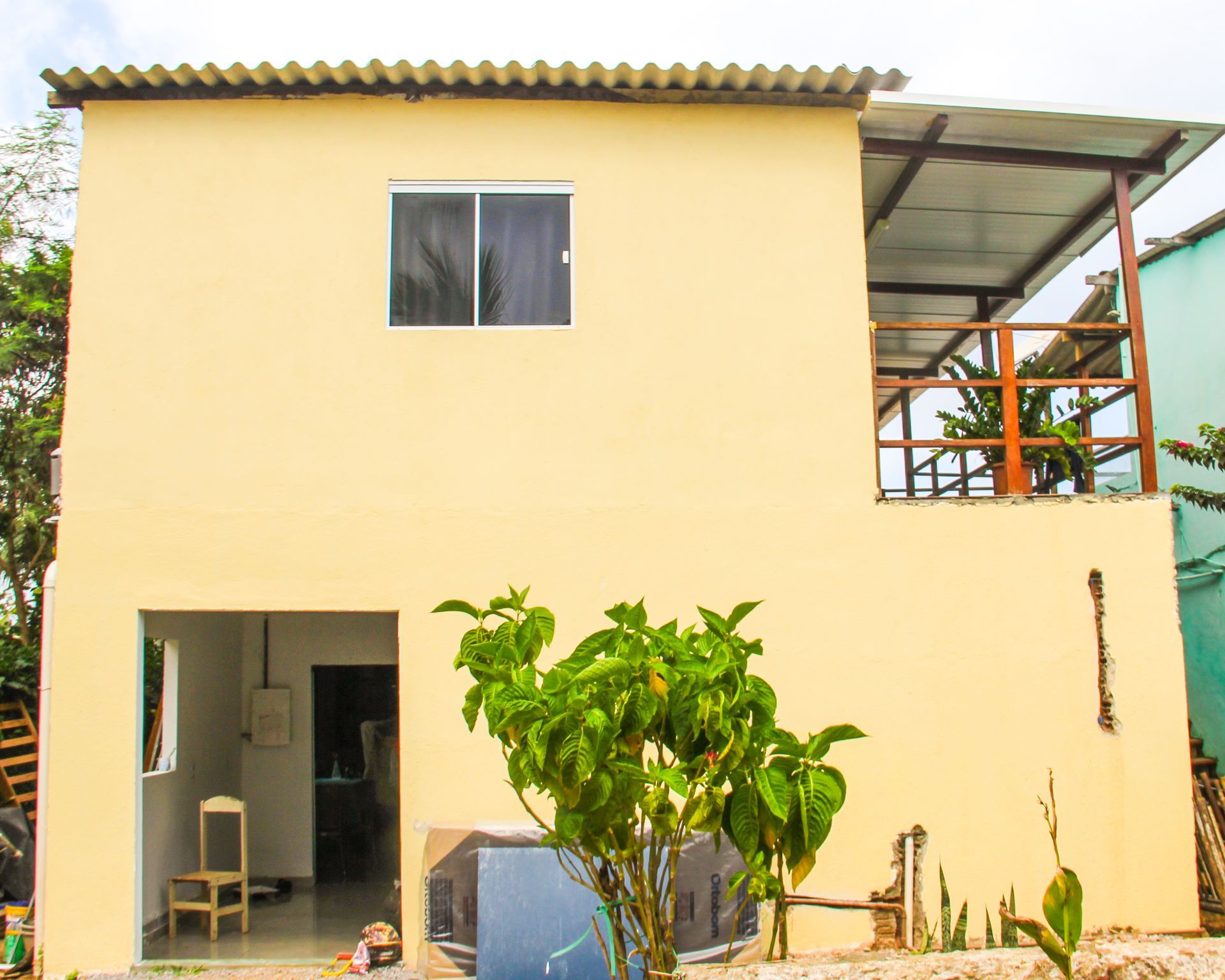 Uma casa amarela com uma varanda e uma árvore na frente