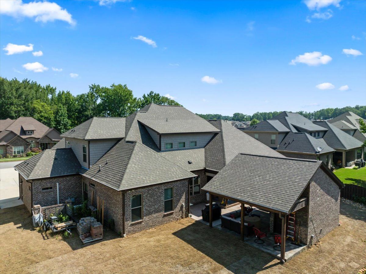 An aerial view of a large brick house with a covered patio.