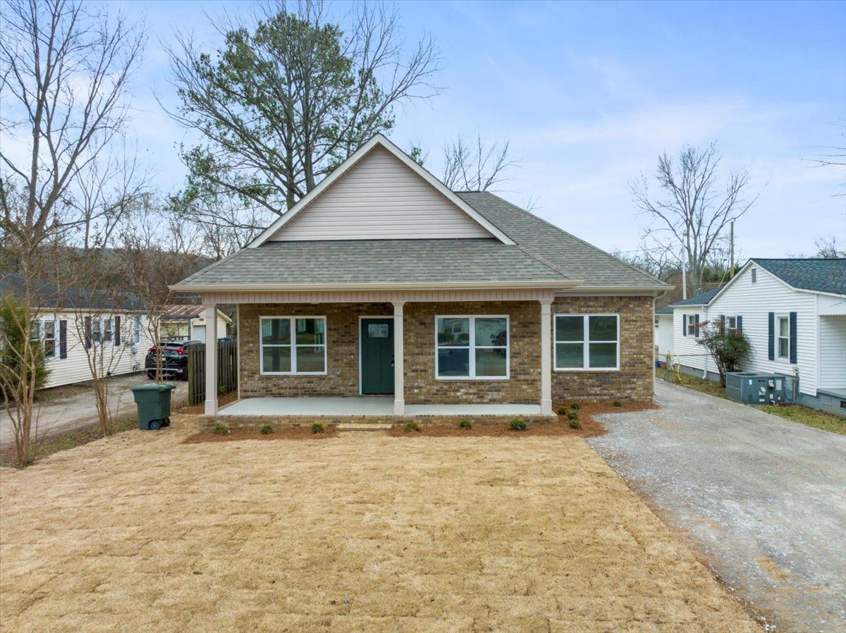 a small brick house with a porch and a lot of windows is for sale .