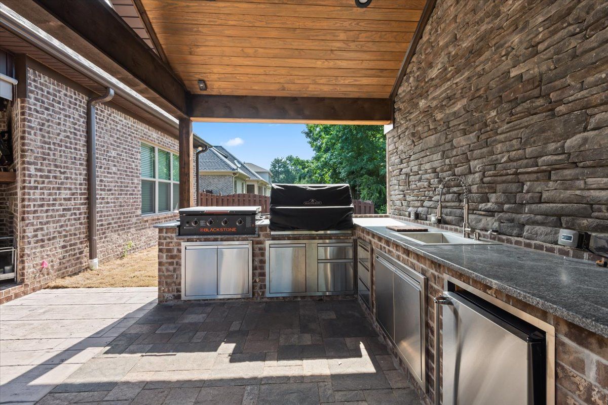 A large outdoor kitchen with a grill and sink