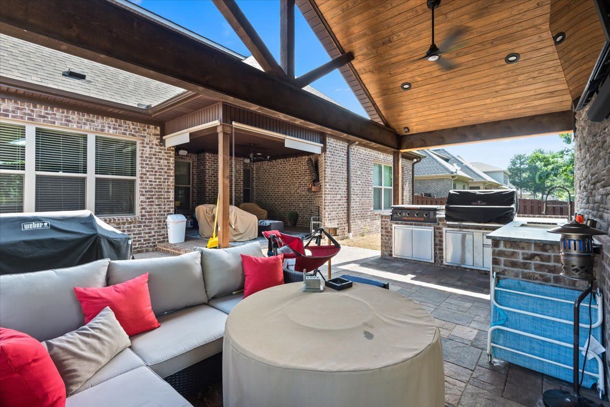 A patio area with a couch , table , and grill.