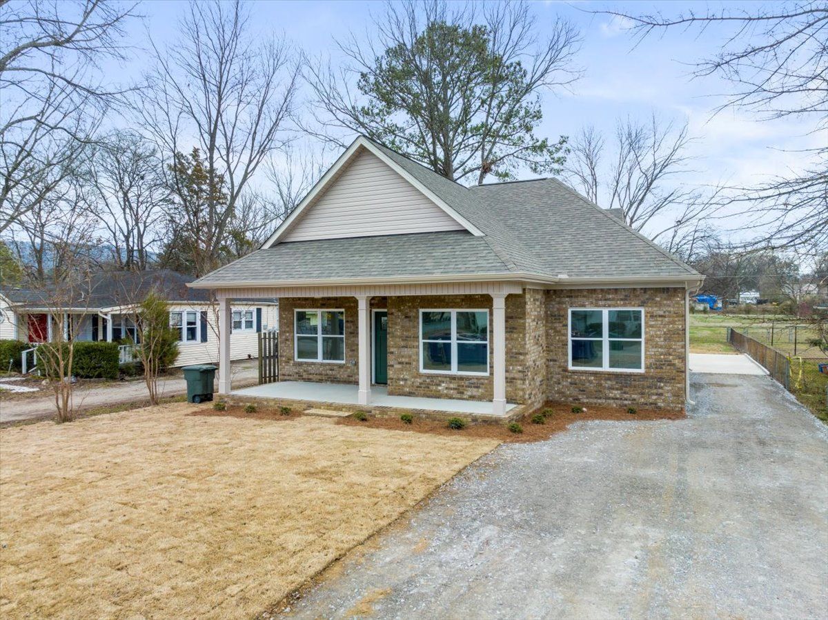 a small brick house with a porch and a driveway .