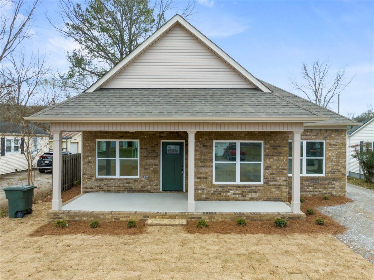 a small brick house with a porch and a green door .