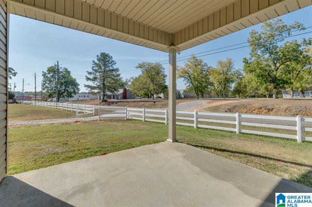 a porch with a white fence and trees in the background