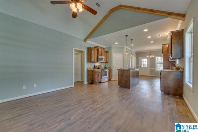 a living room with a ceiling fan and a kitchen in the background