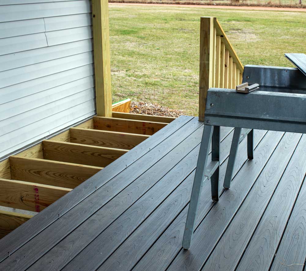 a wooden deck with stairs and a stool on it