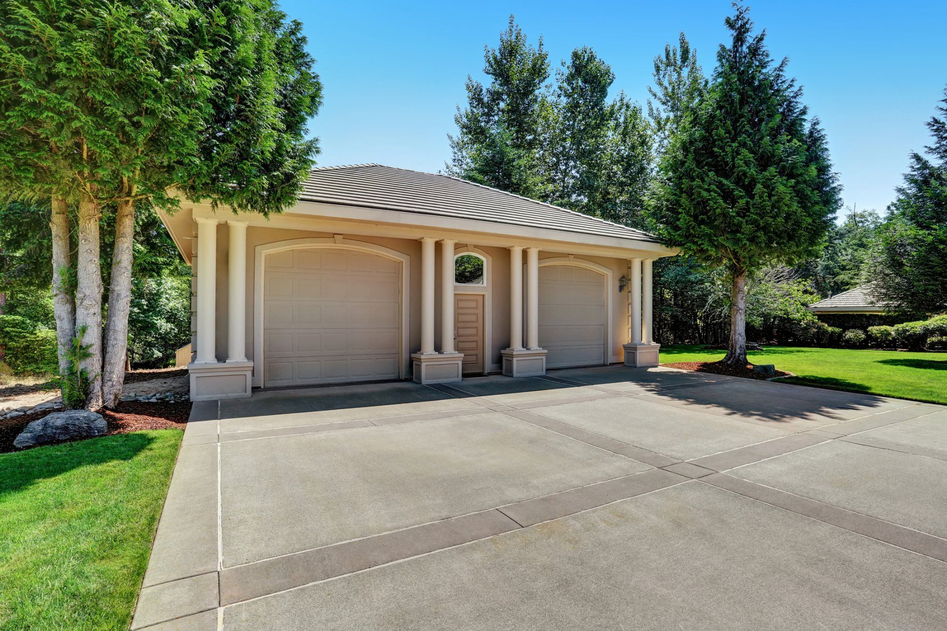 a large garage with a driveway and trees in front of it .