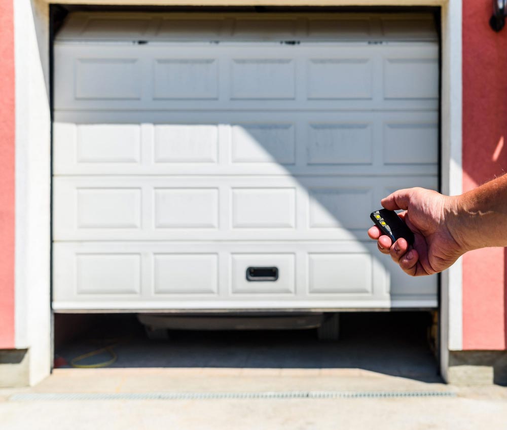 a person is holding a remote control in front of a garage door .