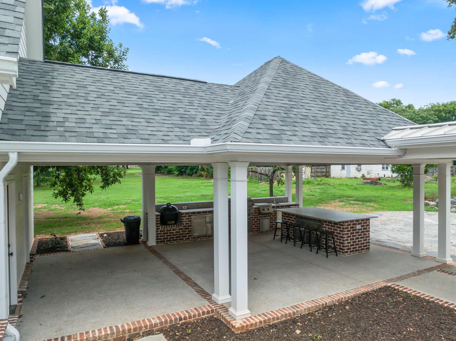 A large covered patio area with a table and chairs under a roof.