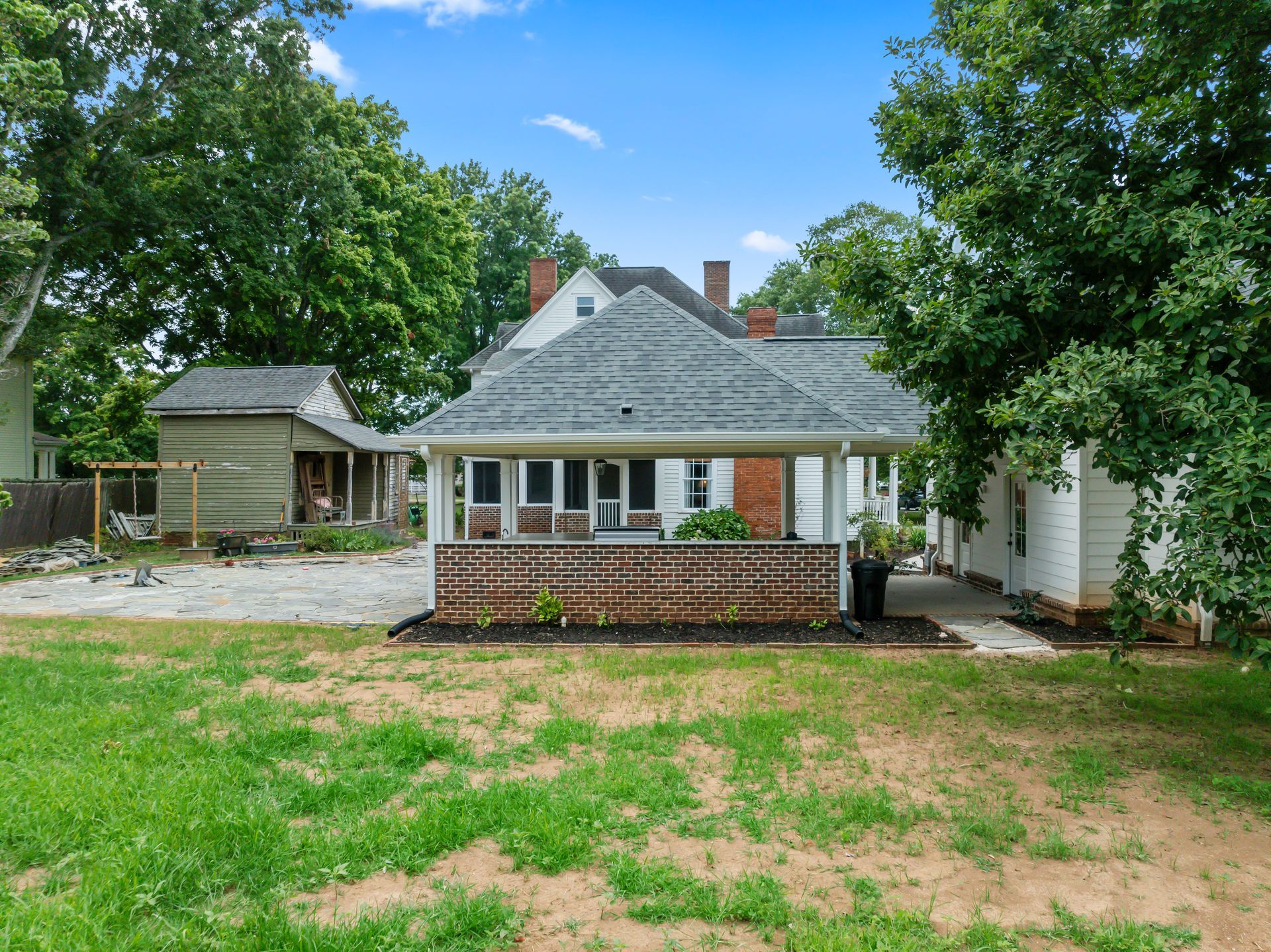 The backyard of a house with a porch and a lot of grass.