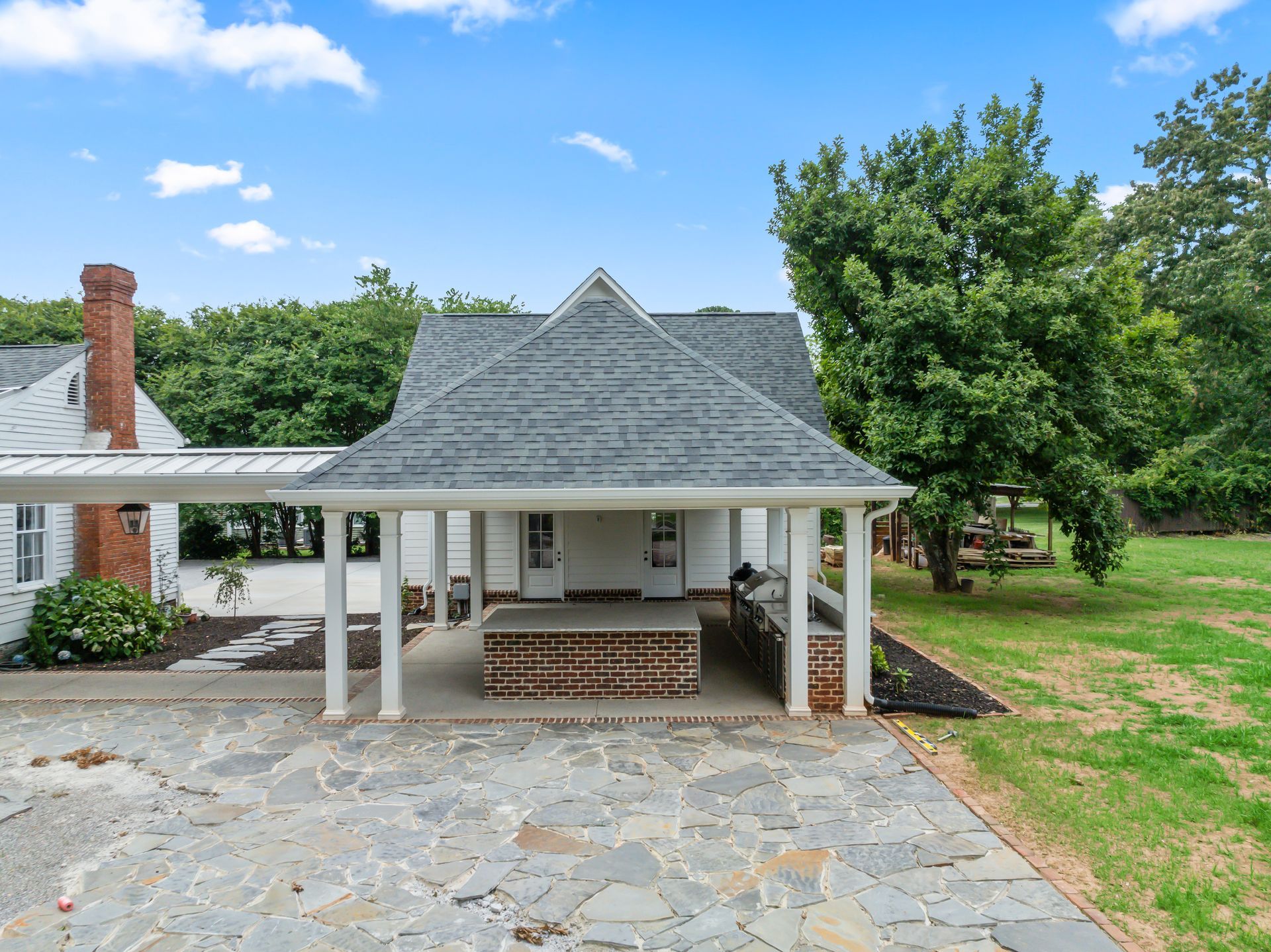 A white house with a gray roof and a stone driveway.