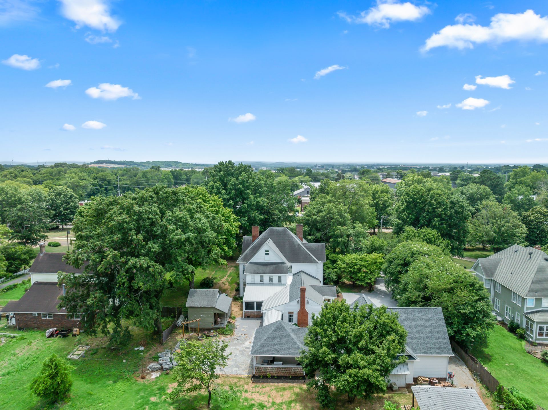An aerial view of a house in a residential area surrounded by trees.