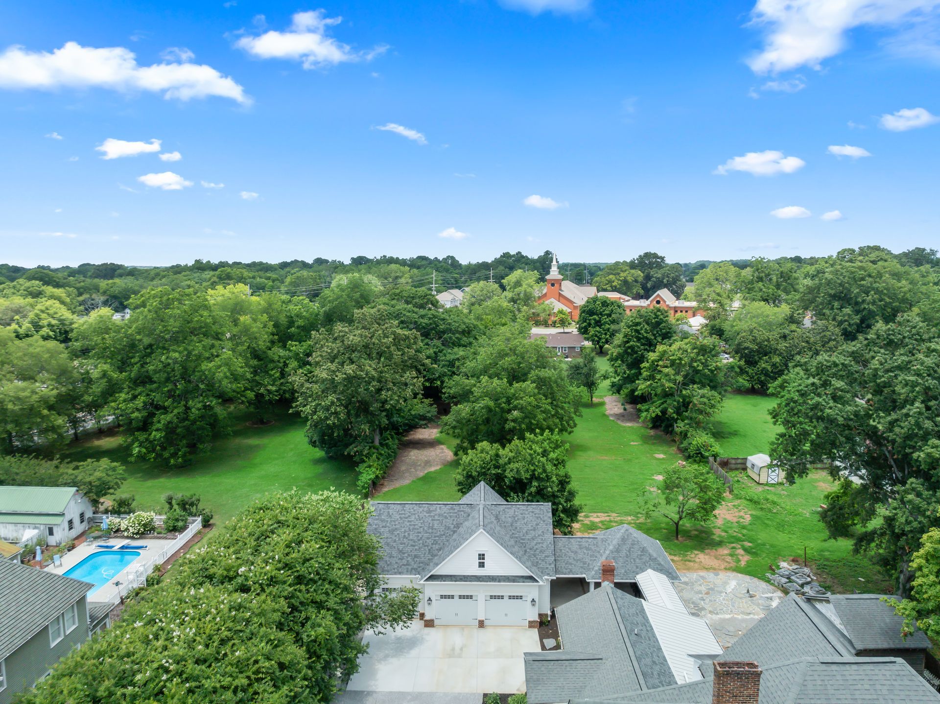 An aerial view of a house surrounded by trees and a swimming pool.