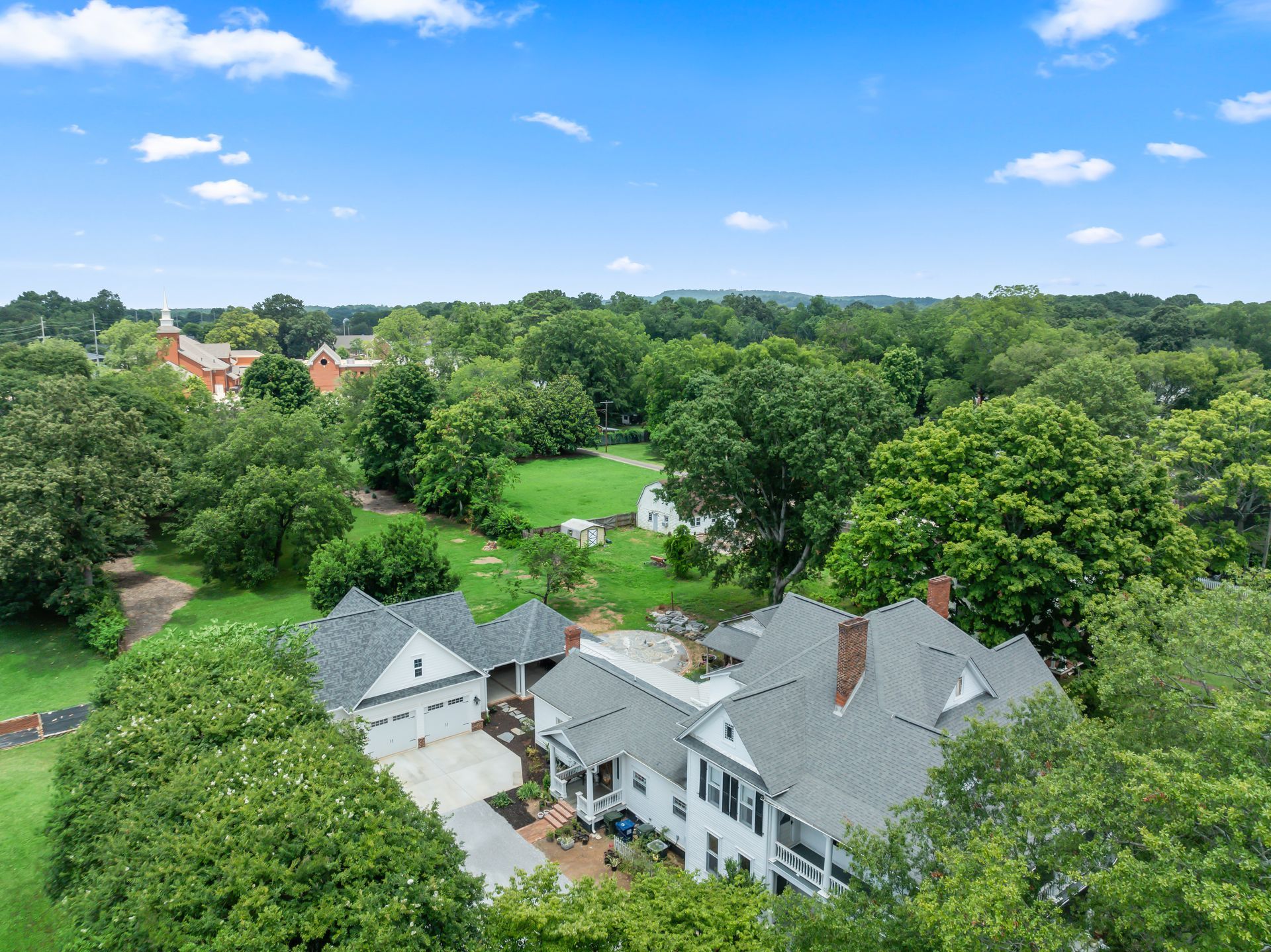 An aerial view of a large white house surrounded by trees.