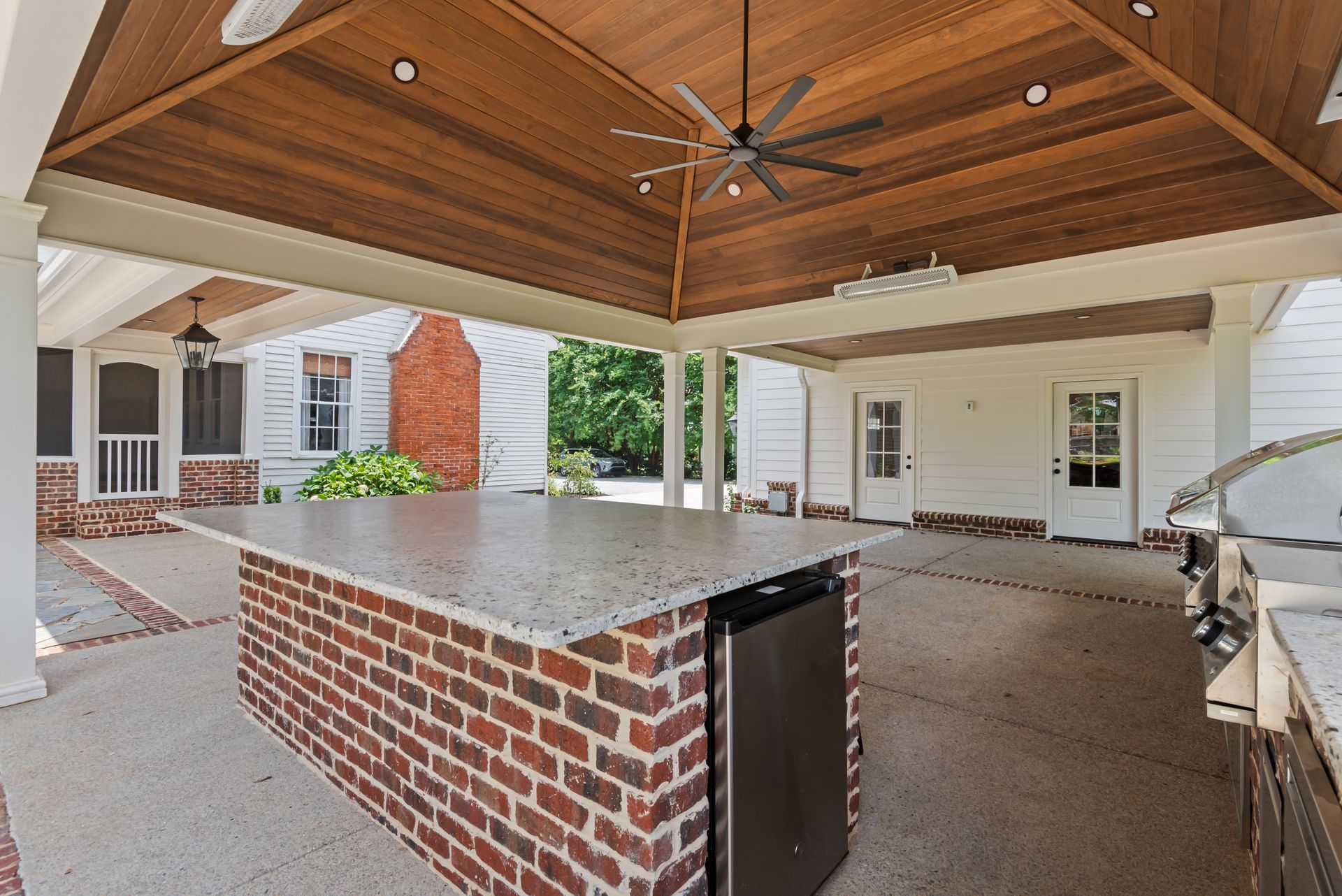 An outdoor kitchen with a brick island and a ceiling fan